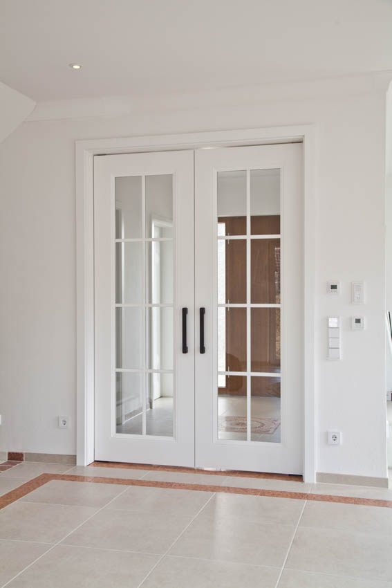 weiße Tür mit Glaseinsätzen und schwarzen Türgriffen